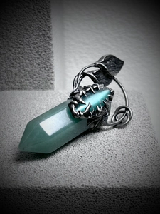 Macro view of green cat-eye crystal pendant with vintage silver vine and claw details