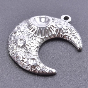 Macro detail of silver stainless steel moon pendant with textured lunar craters