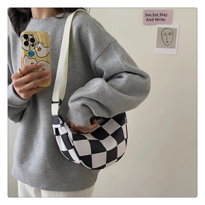 Checkerboard canvas half-moon bag worn with adjustable strap on a casual outfit