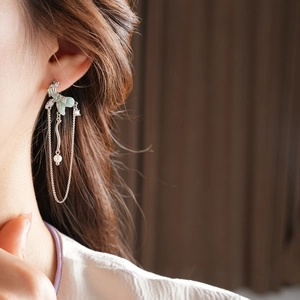 Detail of long silver tassel earring with green petals and pearl on a female model