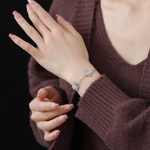 Silver bracelet featuring zircon butterfly charms worn on a wrist for elegant detail