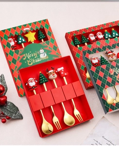Close-up of golden Christmas spoons and forks with cute cartoon silicone handles in gift box