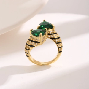 Detail of gold ring featuring pear-cut green stones and black-white enamel stripes