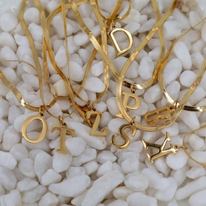 18K gold plated snake chain necklaces with 26 English letter pendants on white pebbles