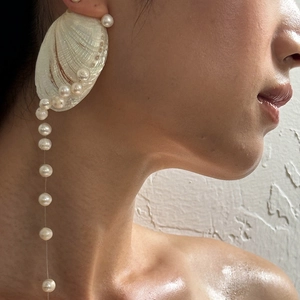 Close-up of long shell and pearl tassel earrings on model during a beach vacation