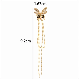 Macro detail of gold butterfly ear cuff with sparkling zircon and long metal tassels