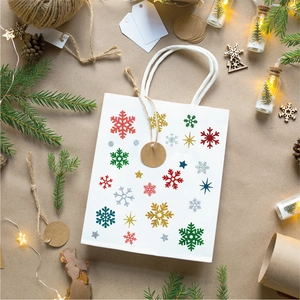 Detailed view of Christmas paper gift bag with glittery snowflake patterns and pine decor