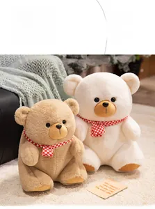 Detail of plush teddy bears in brown and white with decorative red checkered scarves
