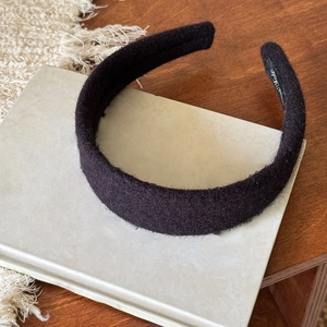 Dettaglio del cerchietto in peluche nero spesso con trama in lana su sfondo libro