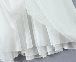 Detailed close-up of layered ruffle hemline on white chiffon backless long dress