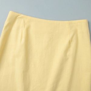 Détail de la texture de la jupe en lin jaune clair avec taille et tissu plissé