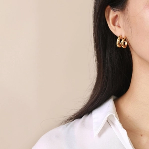 Pendientes de aro geométricos dobles en forma de C de oro de 18 quilates usados por modelo