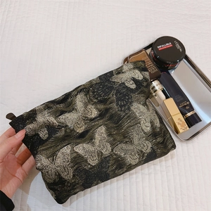 Detailansicht der Vintage-Kosmetiktasche aus schwarzem Brokat mit Goldfalter-Muster