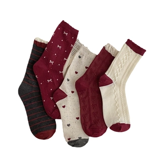 Five pairs of festive red and beige cotton socks with hearts, bows and cable knit patterns