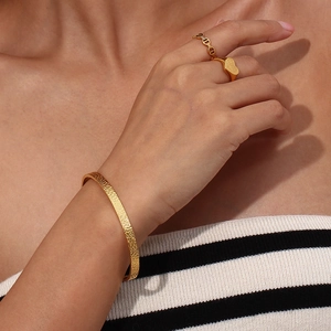 Detailed view of hammered 18K gold plated cuff bracelet and heart signet ring on model