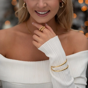Nahaufnahme eines eleganten Goldarmreif- und Ringsets bei einer Frau mit warmem Bokeh