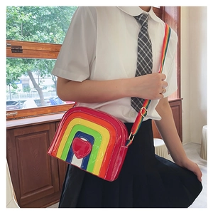 Detail of glossy patent leather rainbow crossbody bag with a red heart patch and wide strap