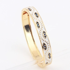 Detail view of gold-plated evil eye bangle with white enamel and blue eye patterns
