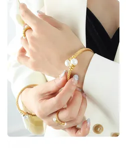 Detail of twisted gold bangle and ring set featuring elegant white pearls on model