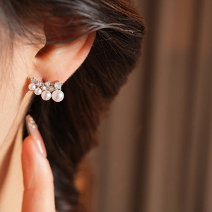 Detailed close-up of 18k gold plated pearl and zircon earrings worn on the earlobe