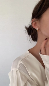 Close-up of gold U-shaped earrings with rectangular cubic zirconia on model