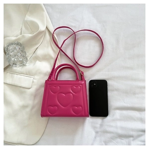 Détail du sac à main rose en cuir PU avec motifs de cœurs gaufrés et longue bandoulière