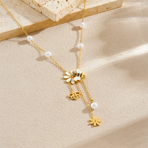 Collana in oro con ciondoli a margherita, un'ape e perle bianche dallo stile chic