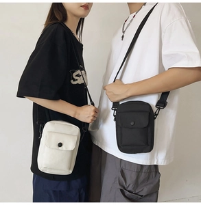 Close-up of minimalist black and white canvas crossbody bags worn by a couple for daily travel
