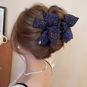 Detail view of a navy blue leopard print bow hair claw clip styled in an elegant hair updo