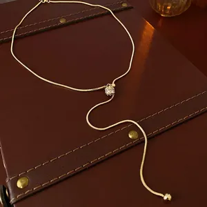 Elegant gold-plated snake chain necklace with zircon pendant on leather background