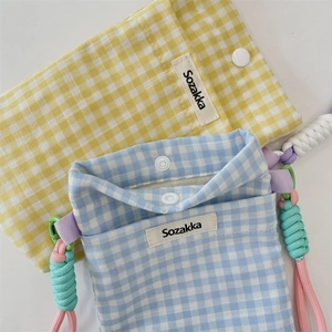Détail de mini sacs en toile à carreaux bleus et jaunes avec bandoulières tressées colorées