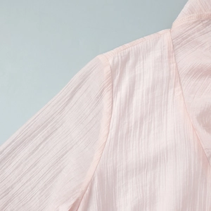 Detailed macro shot of pale pink pleated fabric texture on a long summer V-neck dress