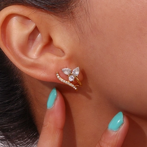 Close-up of gold-plated irregular C-shape earring with sparkling zircon clusters on ear