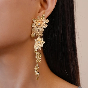 Detailed view of long gold tassel earrings with rhinestone flower and leaf design