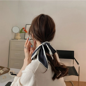 Dettaglio di un elegante elastico per capelli a nastro in seta bianco e nero