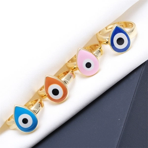 Macro shot of colorful evil eye rings with gold plating on soft white silk fabric