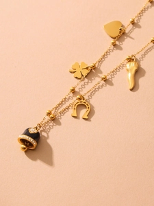 Close-up of 18K gold-plated necklace with horseshoe, clover, and heart charms