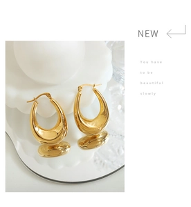 Detail of polished golden U-shaped chunky earrings on a white ceramic display