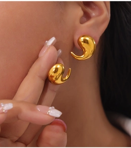 Close-up of gold-plated stainless steel comma earrings with a glossy mirror finish