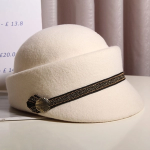 Detail of off-white wool felt beret featuring black gold ribbon and scallop metal buckle