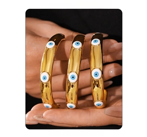 Detailed view of three golden titanium steel bangles featuring blue enamel eye designs
