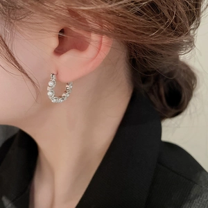 Close-up of silver hoop earrings with small pearls worn by a model in a minimal style