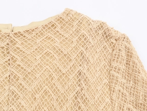 Detailed close-up of beige crochet lace knit fabric showing delicate hollow mesh patterns