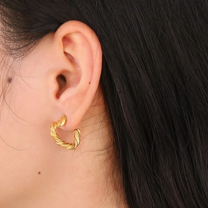 Détail de boucles d'oreilles créoles torsadées dorées avec texture spirale raffinée