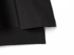 Detailopname van zwarte polyester stof met zoomrand en zachte gedrapeerde textuur