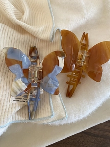 Detail of elegant butterfly hair claws in marble and amber acetate for bun styling