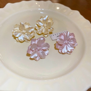 Macro shot of camellia flower earrings with pearlescent petals and pearl centers