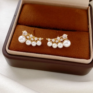 Detail of 18k gold plated earrings featuring zircon stones and gradient white pearls