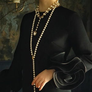 Elegante collana di perle a più strati con dettagli dorati indossata da una modella