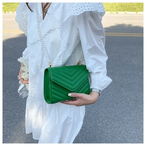 Close-up of vibrant green quilted crossbody bag with luxury pearl chain strap and V-pattern